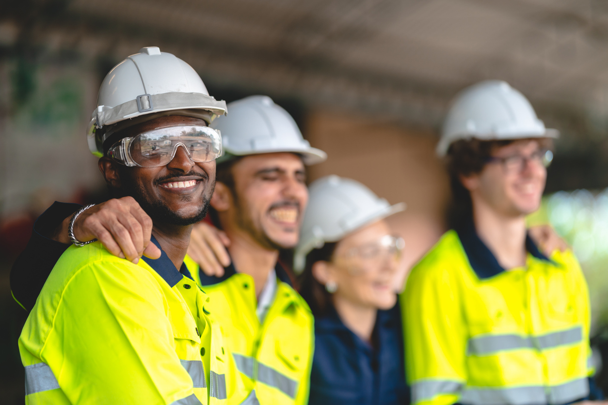 Group of construction workers smiling in safety gear and hard hats
