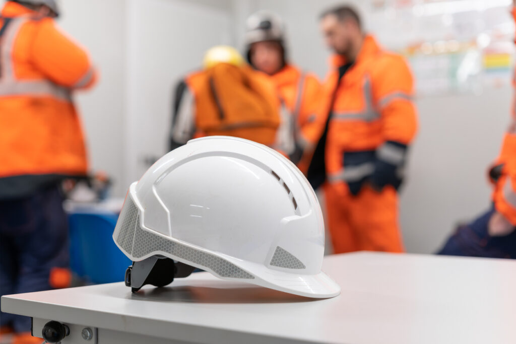 Hard hat on table during pre-shift safety meeting, representing the importance of training and communication during Management of Change (MOC) procedures.