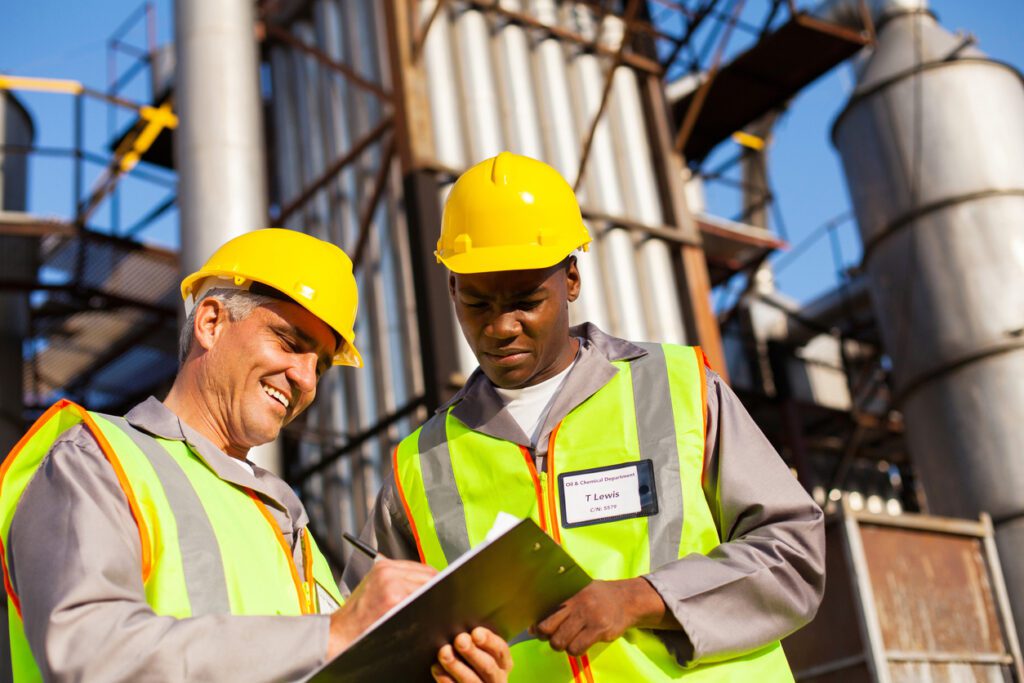 Two industrial workers in hard hats and high-visibility vests review a clipboard at a ResponsAble plant site.