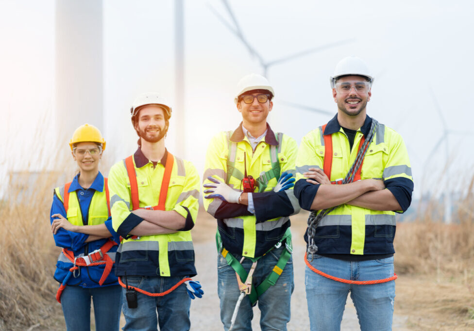 Portrait of male and female engineers wearing uniform and helmet preparing for working at wind turbines farm