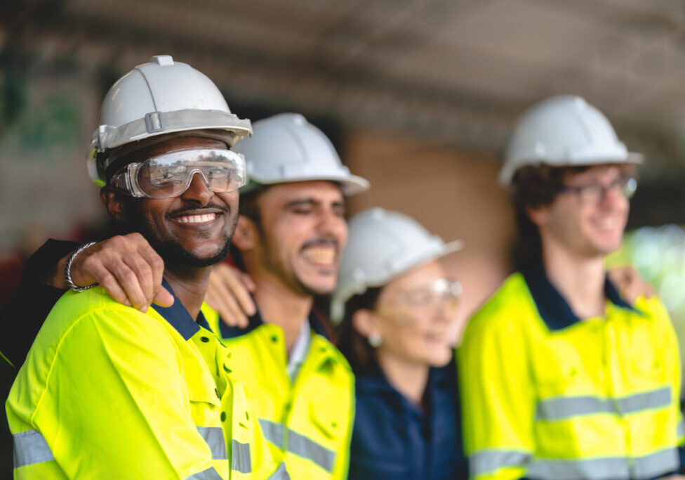Happy Safety Team on Job Site Group of construction workers smiling in safety gear and hard hats