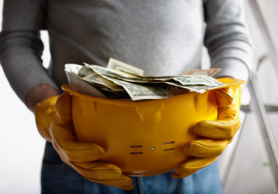 financial concept with dollars and yellow hardhat, selective focus on nearest part