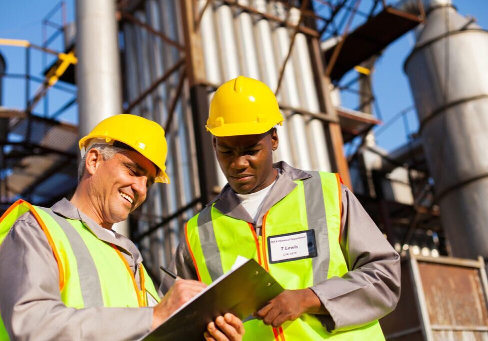 Two industrial workers in hard hats and high-visibility vests review a clipboard at a ResponsAble plant site.