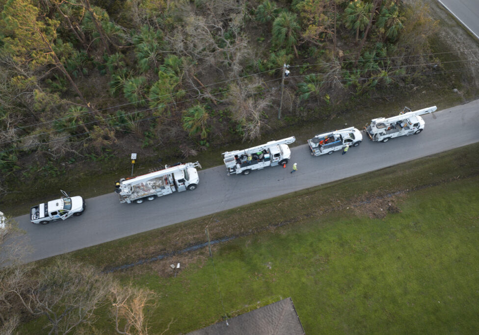 Electrical service company restoring power repairing damaged power lines after hurricane in in Florida suburban area.