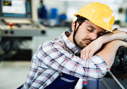 Tired overworked worker falls asleep during working hours in factory