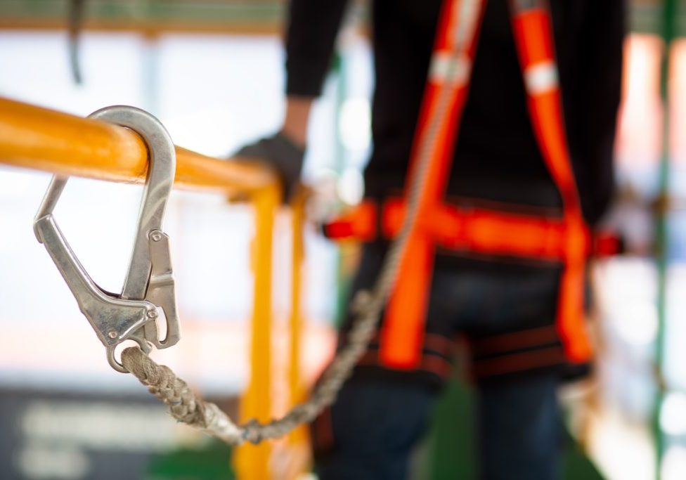 Construction worker use safety harness and safety line working on a new construction site project.